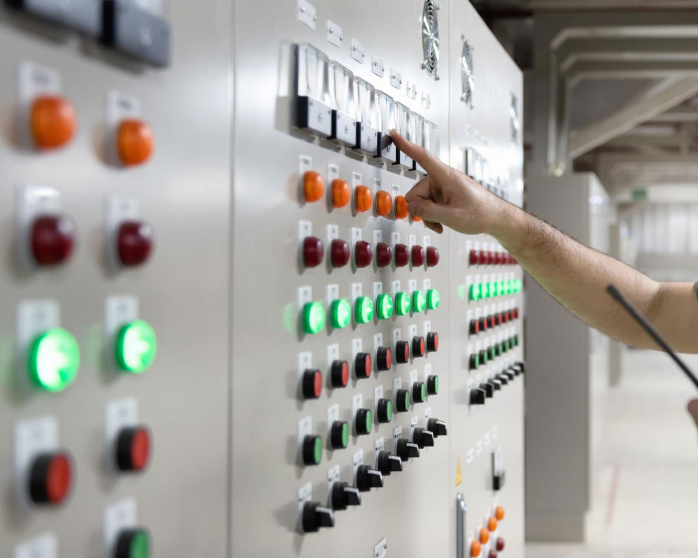 En hand som trycker på en knapp på ett styrsystem